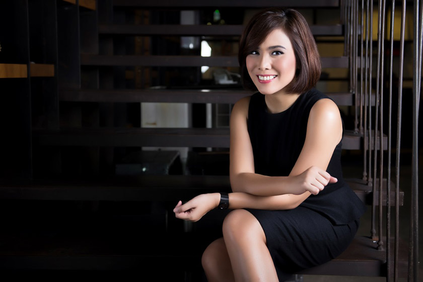 A woman with black dress sitting on stairs and smiling